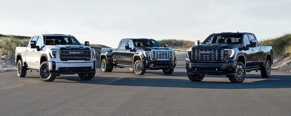 Three 2025 GMC Sierra 2500s parked on a beach road