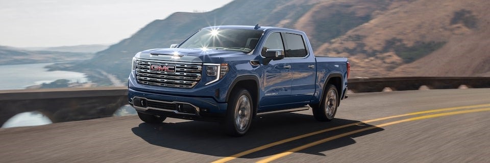 Blue 2025 GMC Sierra driving on a scenic route