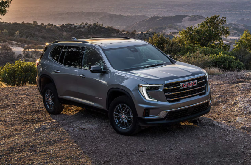 A gray GMC Acadia on a dirt road in a mountainous area.