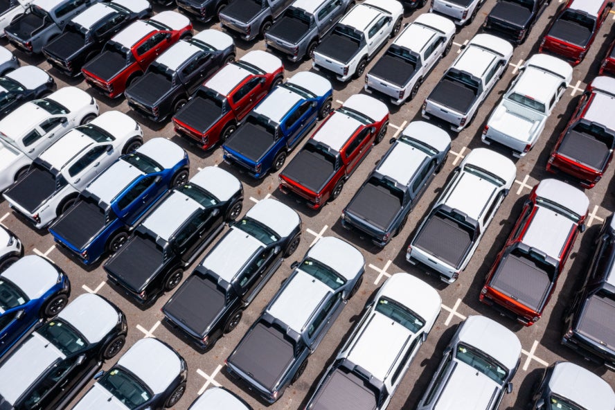 An aerial view of many pickup trucks in a sales lot.